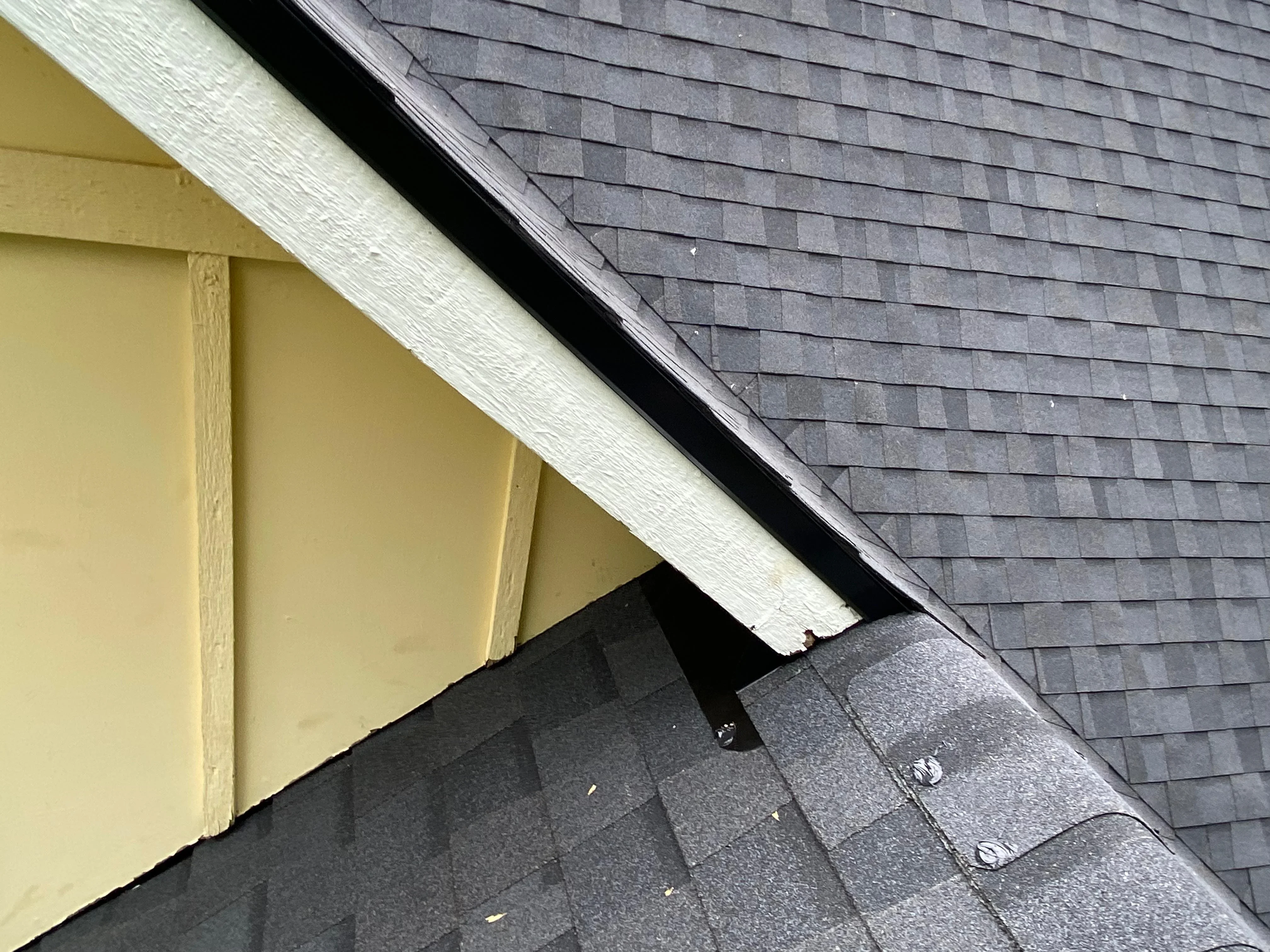 Dark gray asphalt shingles installed on roof with white fascia trim and soffit