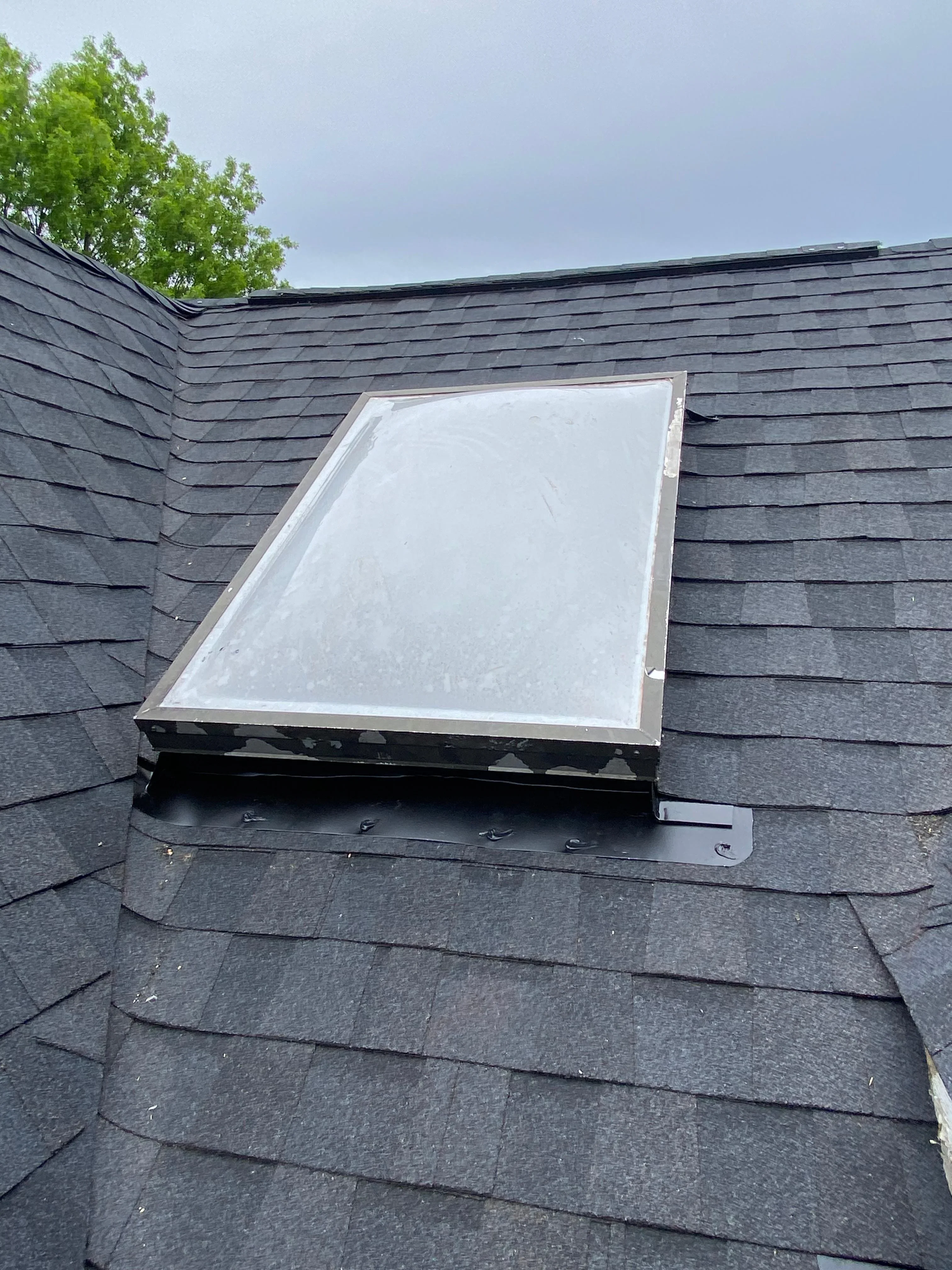 White-framed skylight installed on dark asphalt shingle roof with proper flashing and sealing