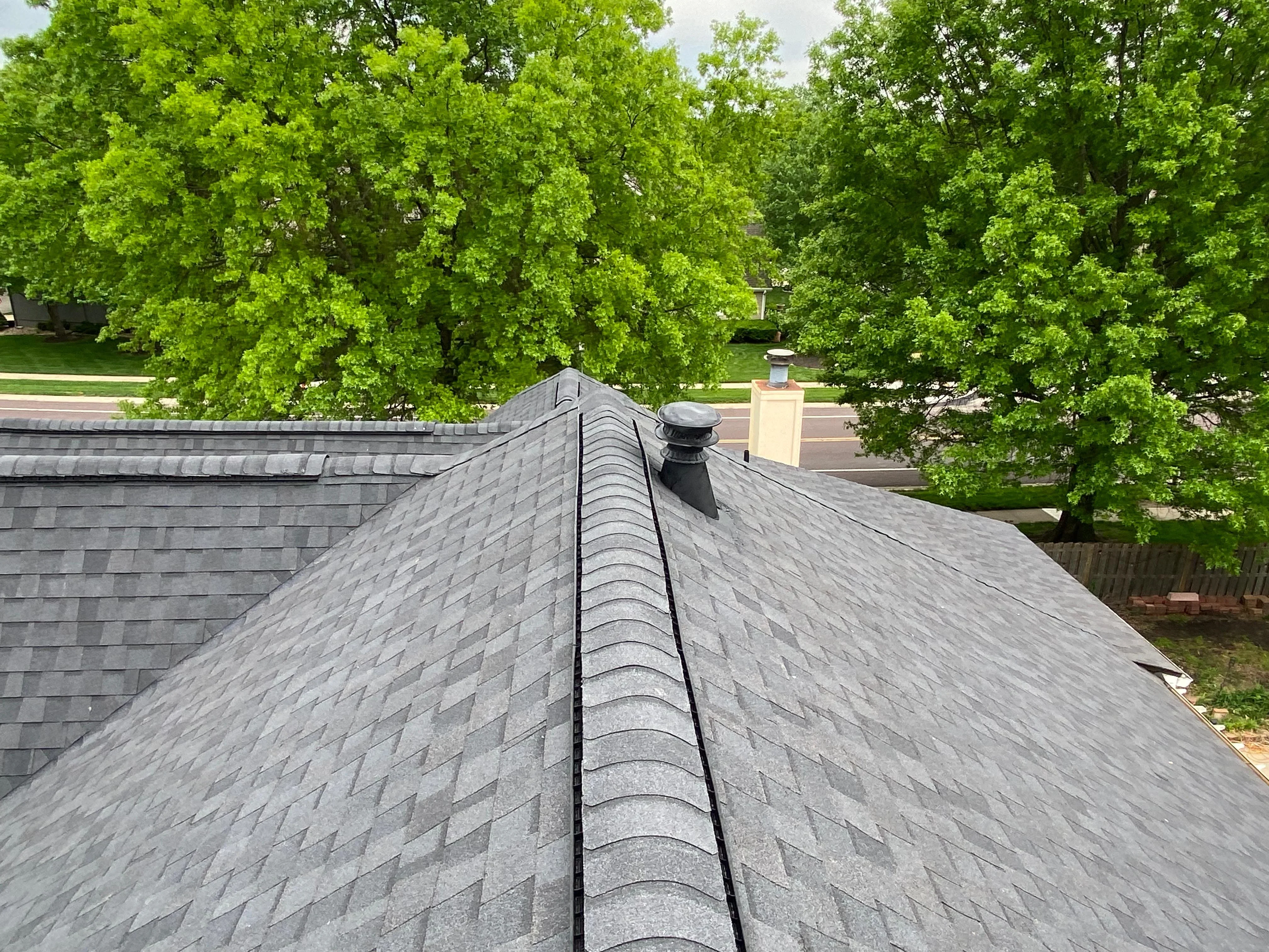 Charcoal gray architectural shingles with ridge cap on pitched residential roof