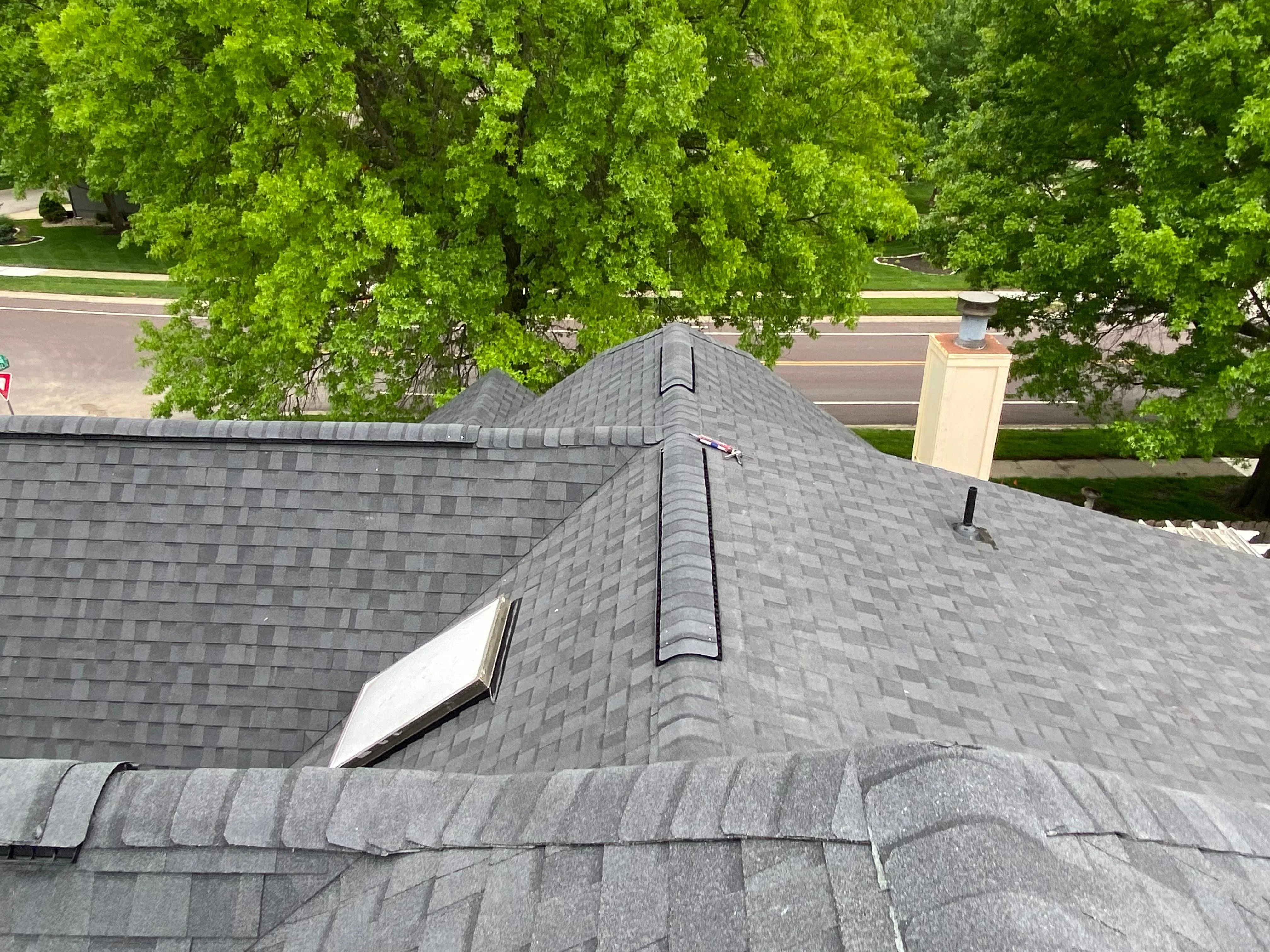 Gray architectural shingle roof with ridge cap and roof vents installed on residential home