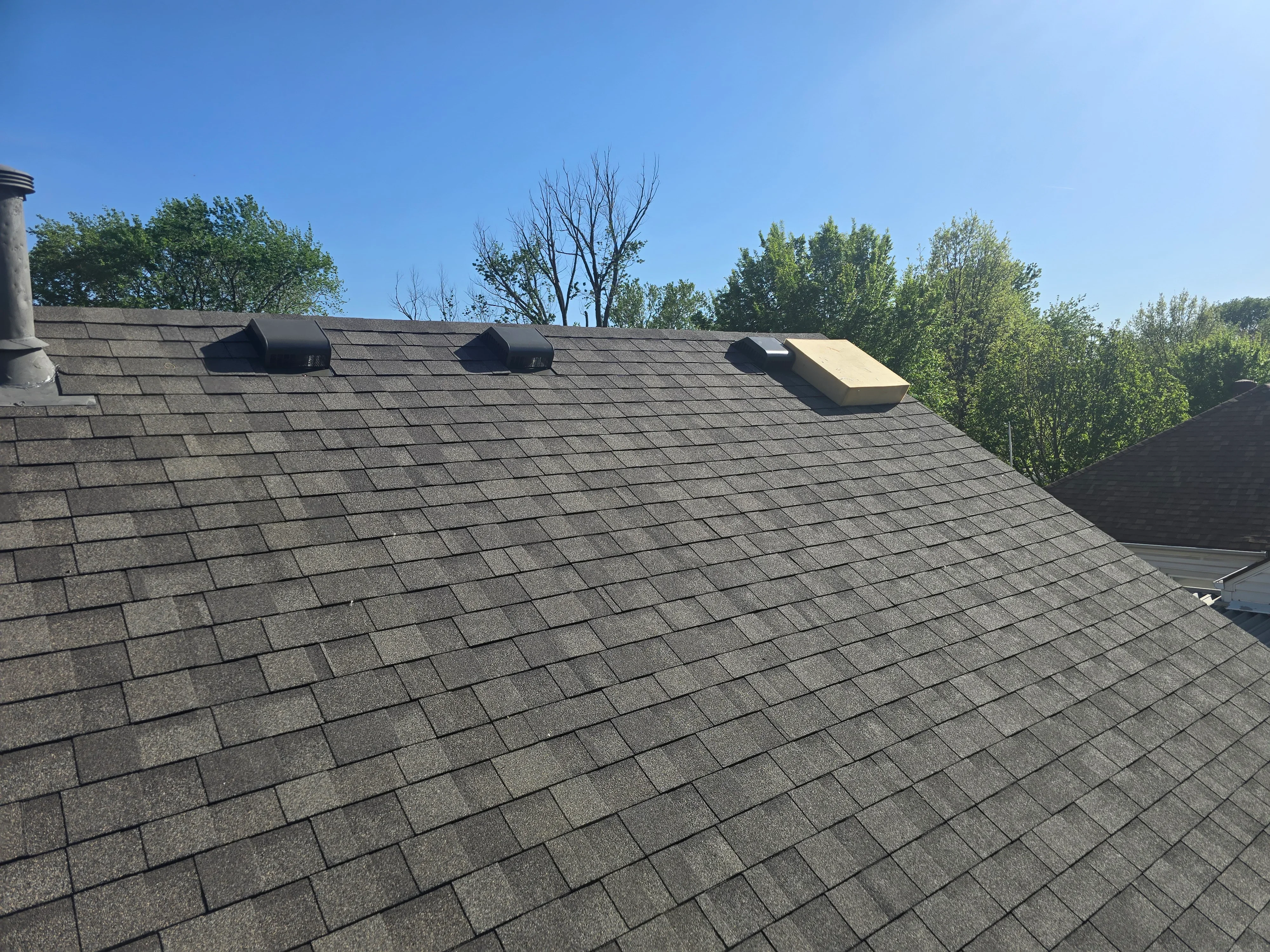 Gray architectural shingles with three roof vents installed on pitched roof