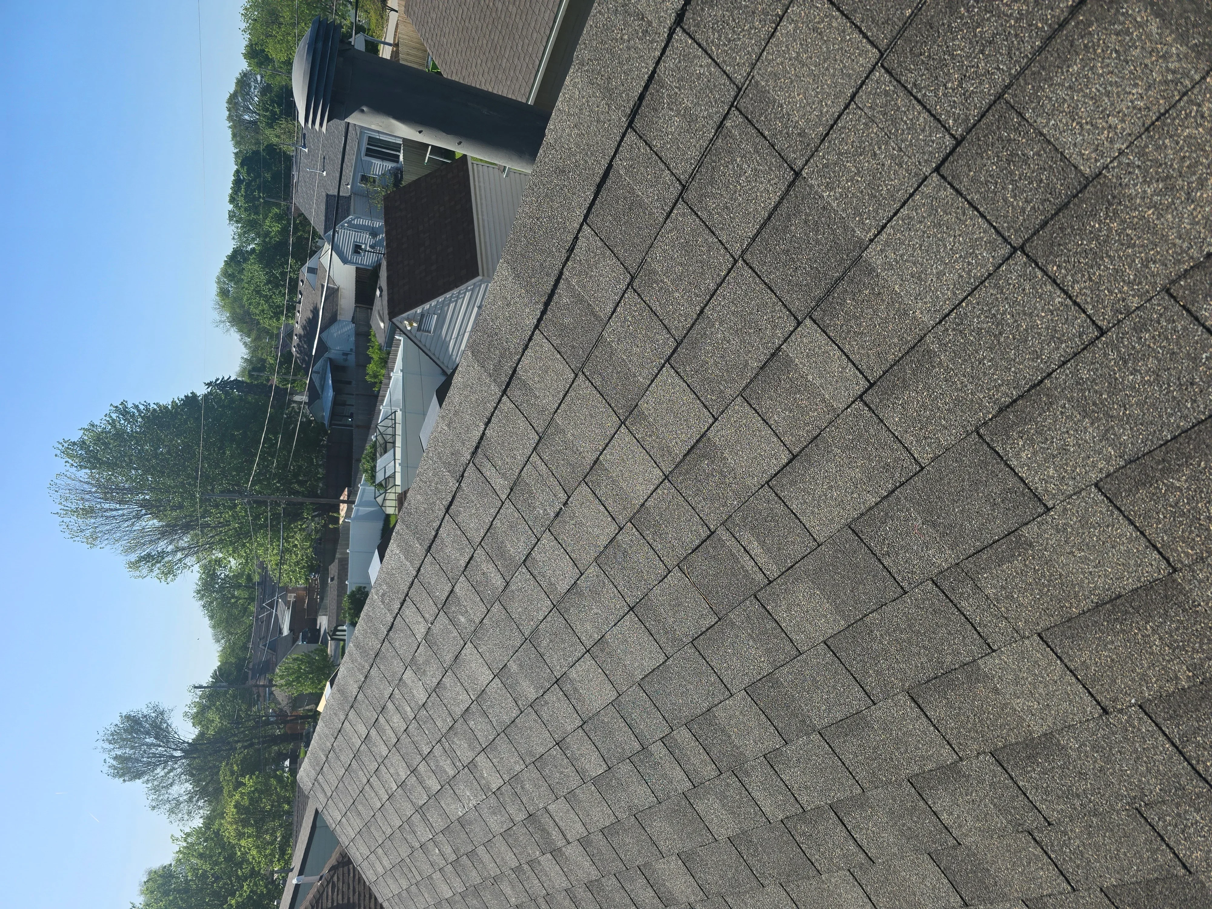 Herringbone pattern asphalt shingle roof installation in charcoal gray