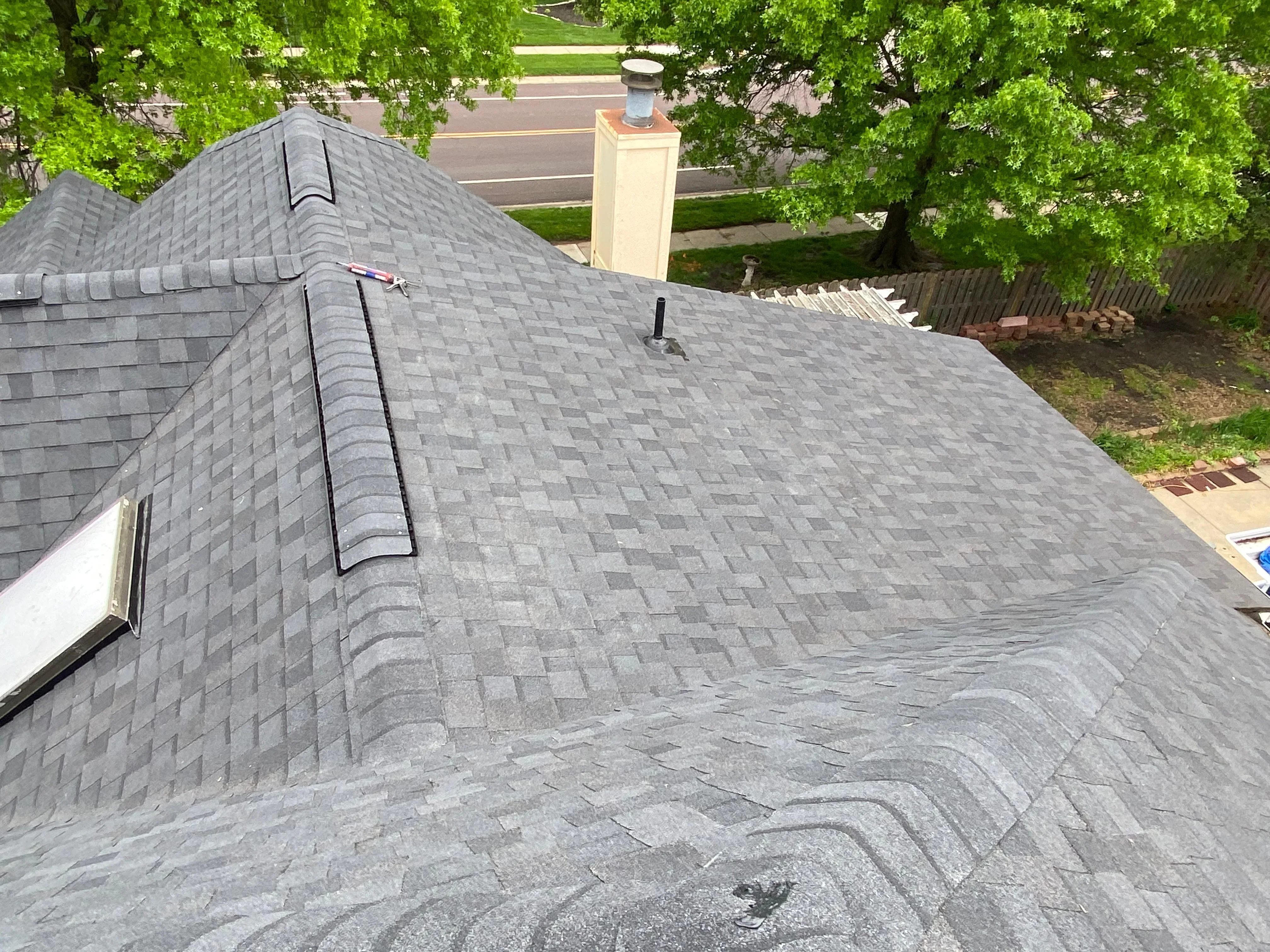 Gray dimensional asphalt shingles installed on multi-plane roof with chimney flashing and ridge vent