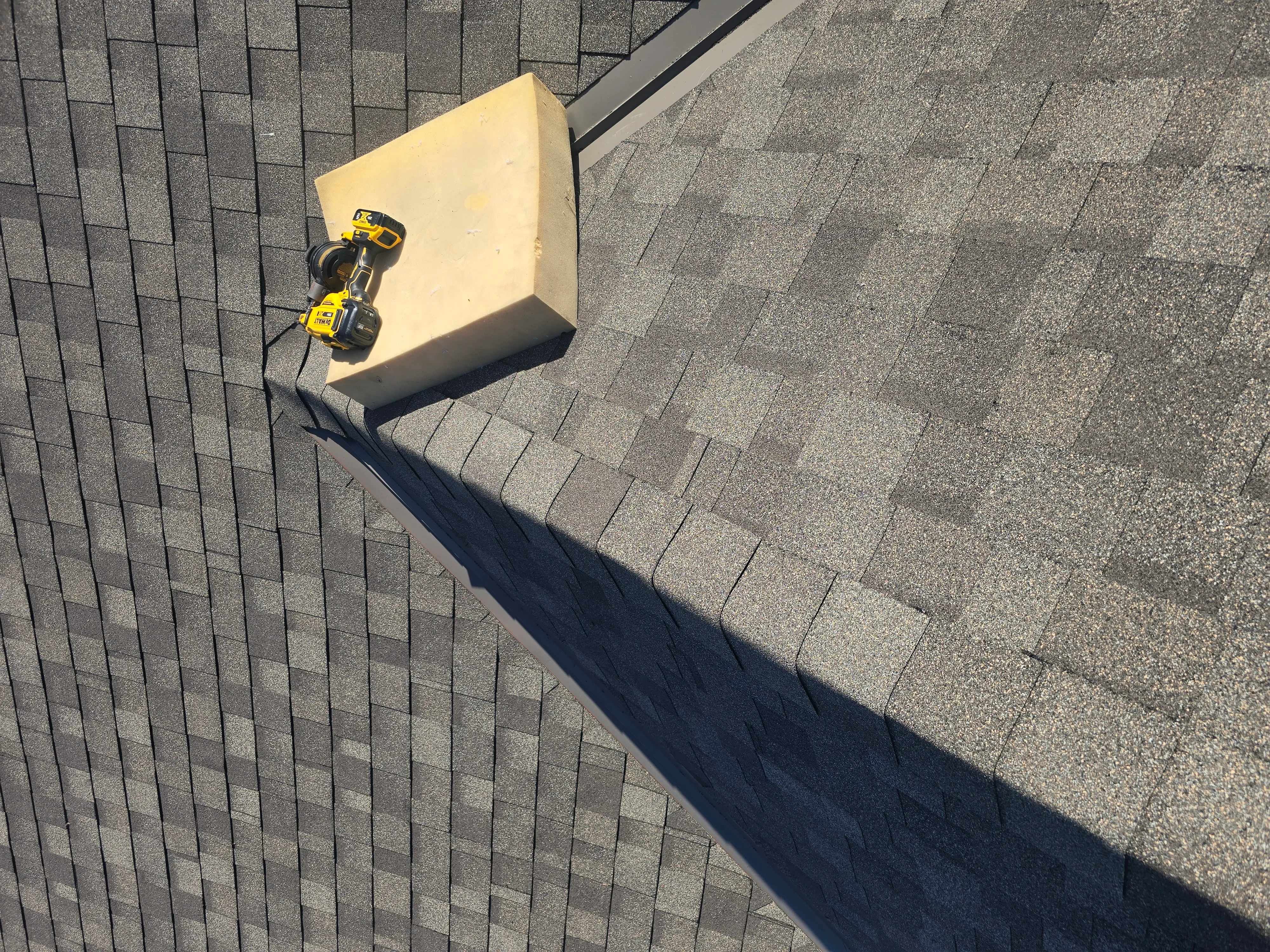 Gray asphalt shingles installed in staggered pattern with metal flashing along roof edge