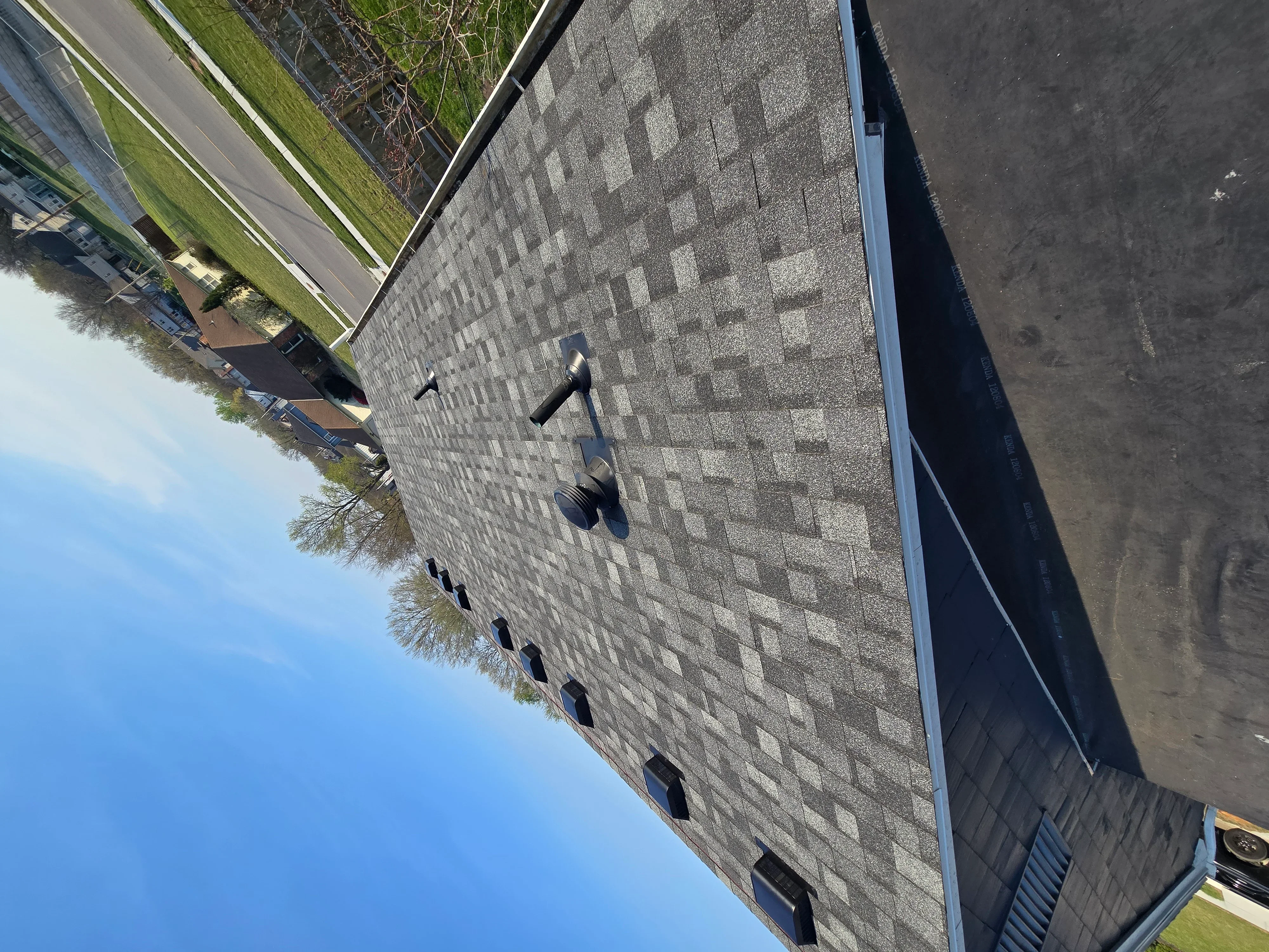 Gray architectural shingles with two-tone pattern, soffit vents, and integrated gutters