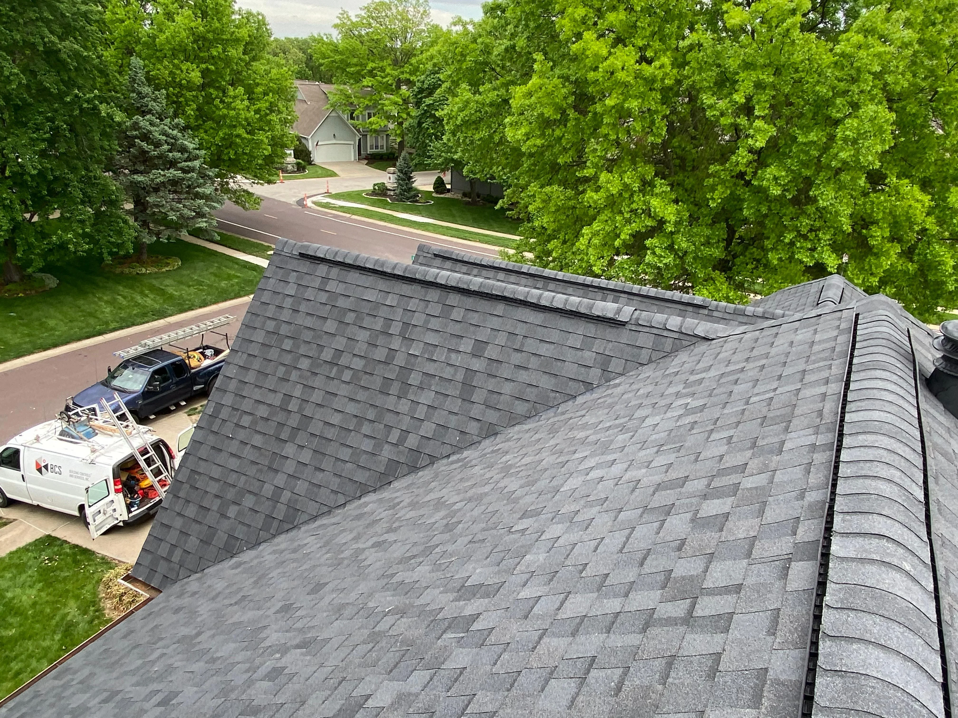 Charcoal gray architectural shingles installed on residential roof with ridge cap and flashing details